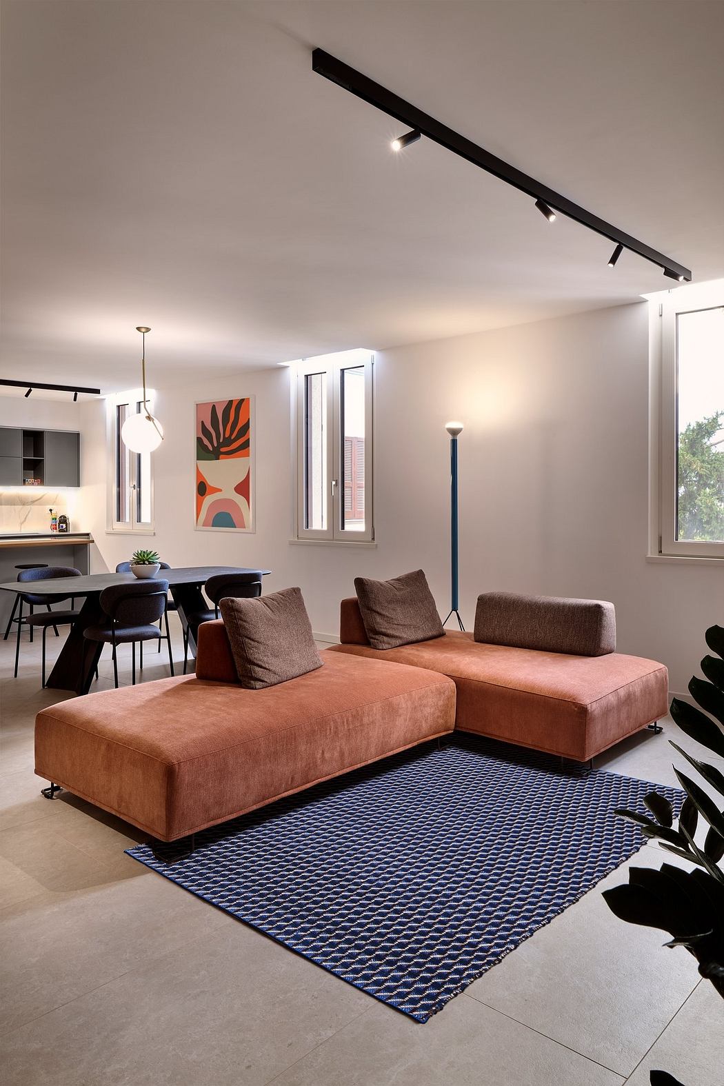 Sleek, minimalist living space with patterned rug, modern furniture, and bright artwork.