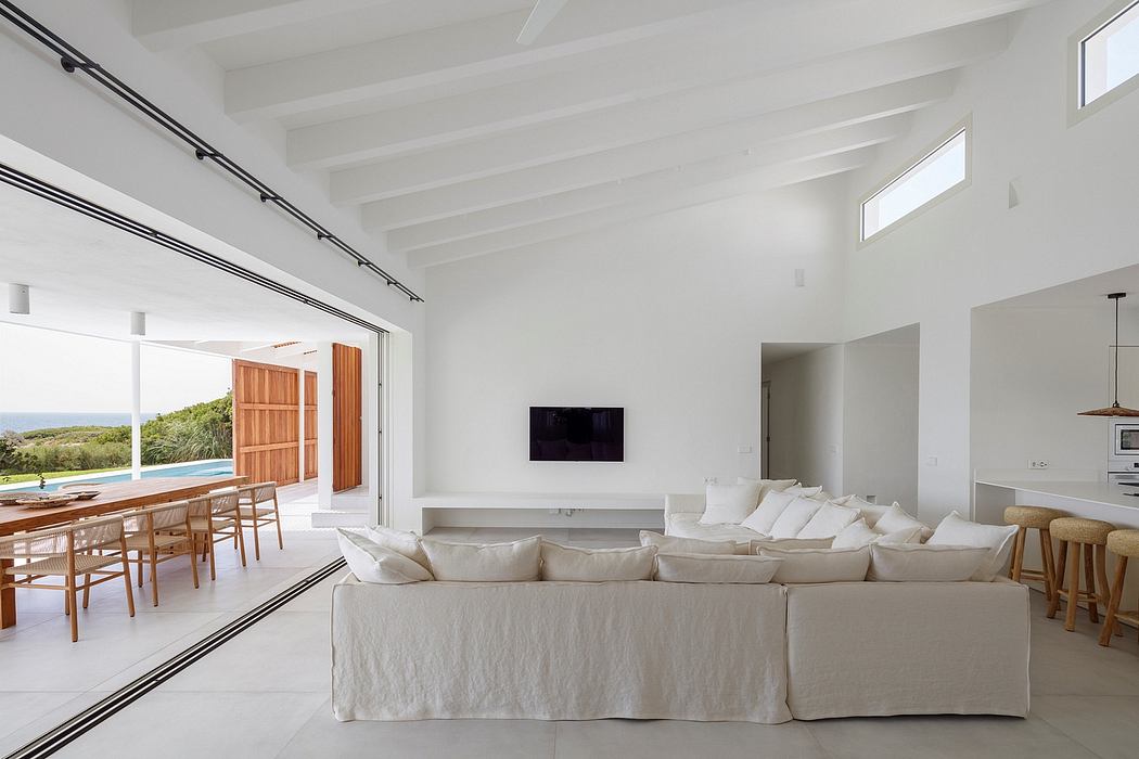 Bright, open-concept living space with vaulted white ceilings, large windows, and modern furnishings.