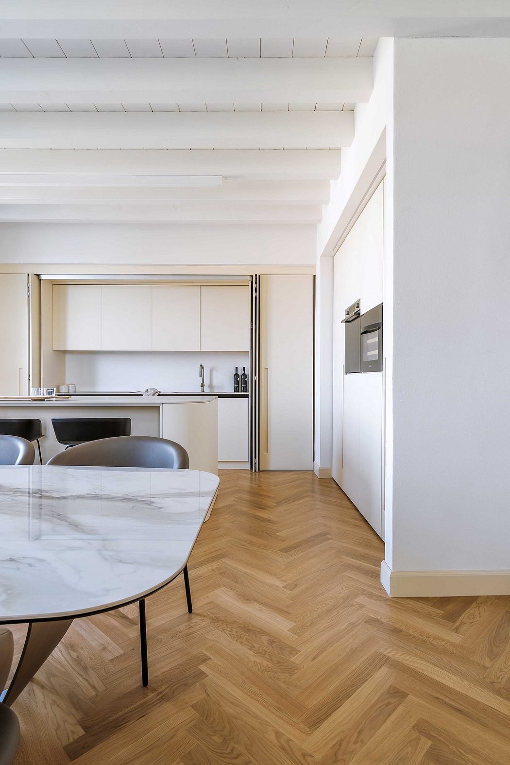 Modern kitchen with clean lines, marble countertop, and herringbone wood flooring.
