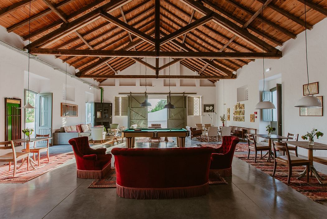 Spacious open-plan living area with rustic wooden ceiling beams and plush red furniture.