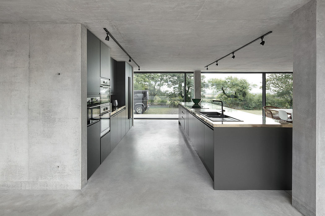 Minimalist kitchen and dining area with concrete walls, sleek cabinets, and panoramic window.