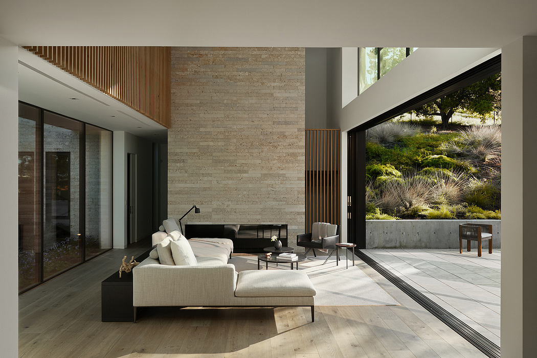 Spacious modern living room with wooden accents, large windows, and a view of the outdoor landscaping.