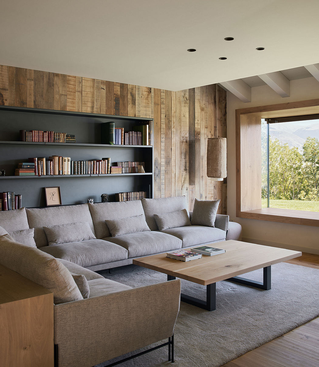 A cozy living room with a modern rustic aesthetic, featuring wooden walls, plush gray sofas, and a wooden coffee table.