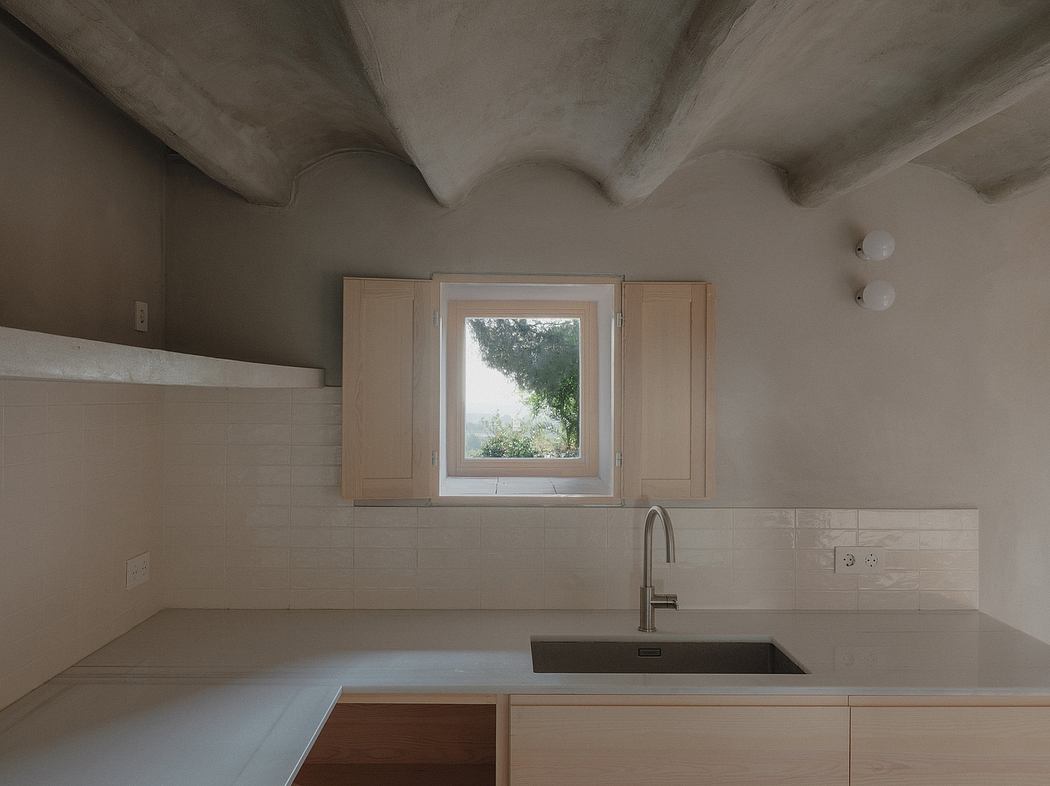 A modern kitchen with clean lines, wood cabinets, and a large window overlooking nature.