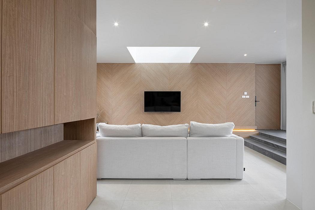 Modern living room with chevron-patterned wood walls, built-in shelving, and a large white sofa.