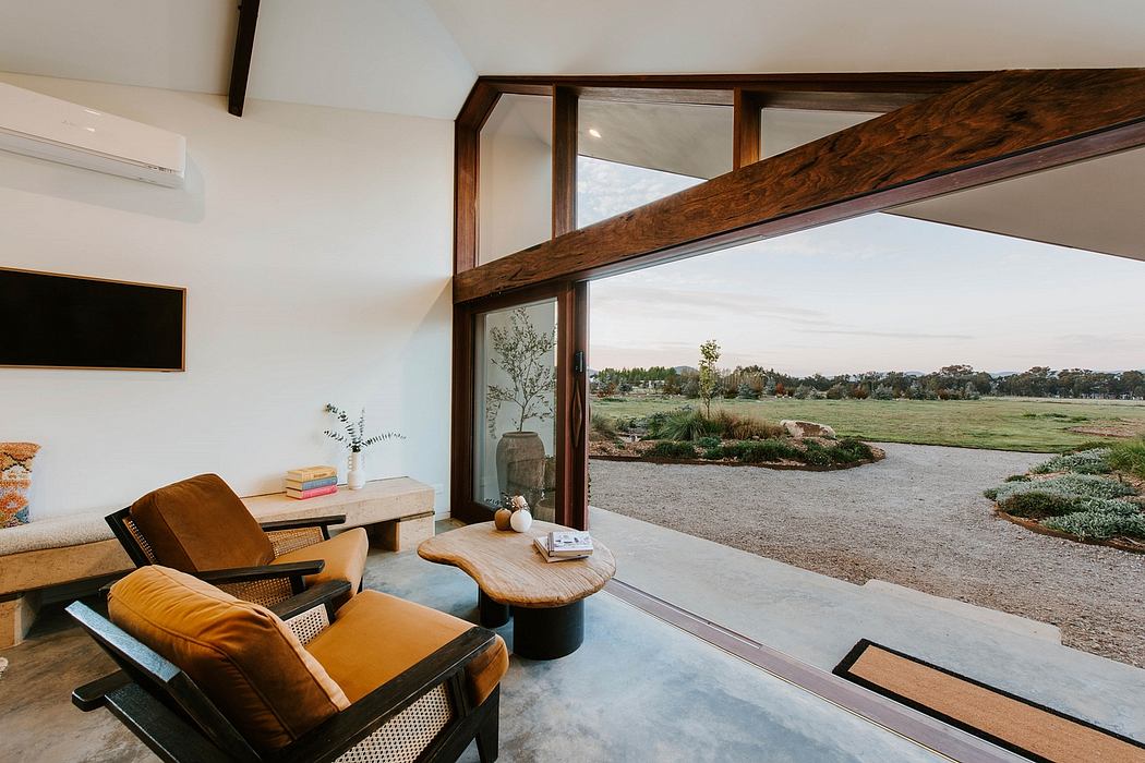 Cozy living space with wooden beams, large windows overlooking outdoor scenery.