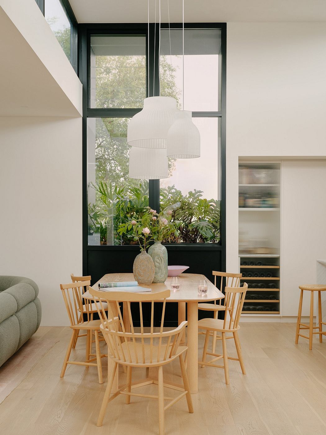 Bright, modern dining room with large windows, wooden furniture, and potted plants.