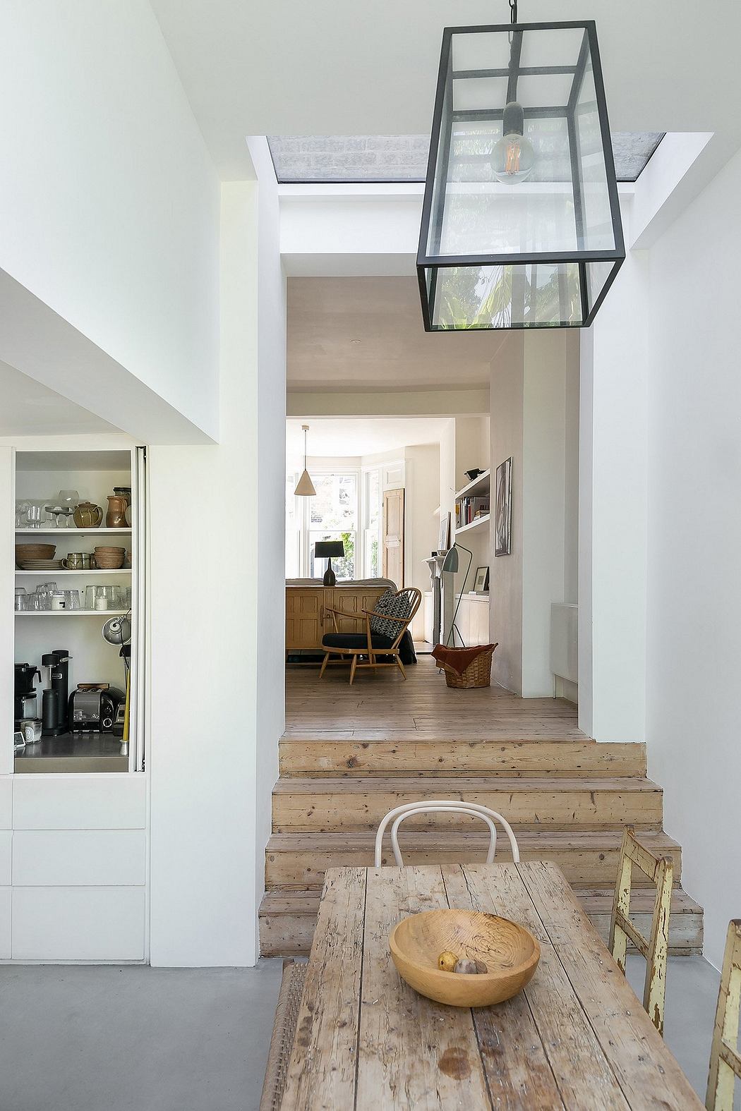 Well-designed interior with wooden steps, shelves, and an elegant glass pendant light.