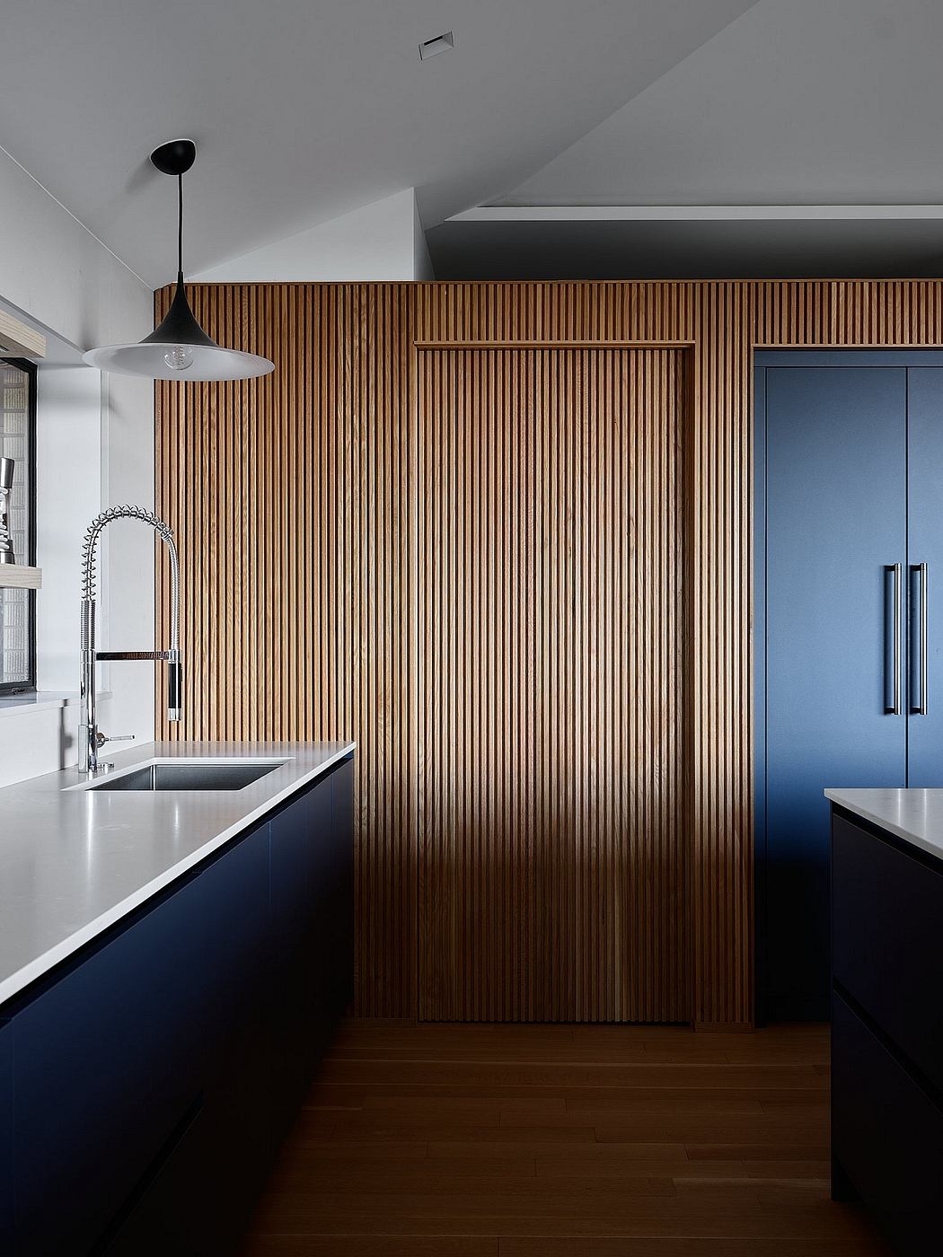 A modern kitchen with a striking wooden slat wall and stainless steel appliances.