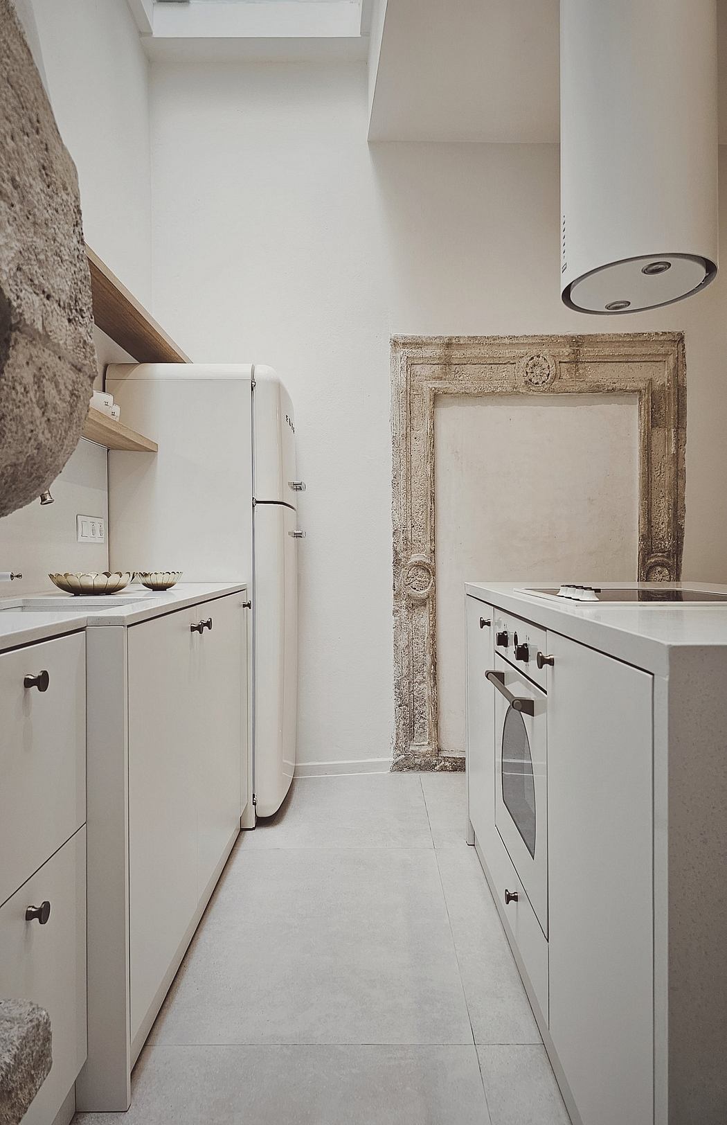 A modern, minimalist kitchen with vintage architectural details and built-in appliances.