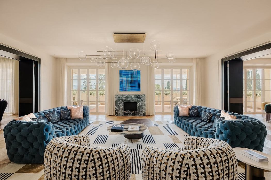Luxurious living room with tufted blue sofas, modern chandelier, and patterned rug.