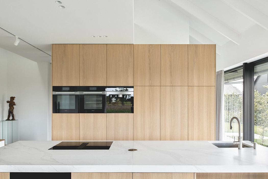A modern kitchen with a sleek wooden cabinetry, built-in appliances, and a large marble countertop.
