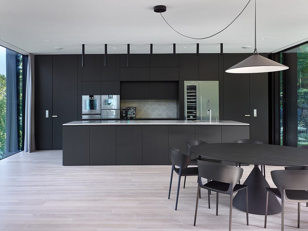 Sleek black cabinets, minimalist lighting, and a modern dining table in a contemporary kitchen.