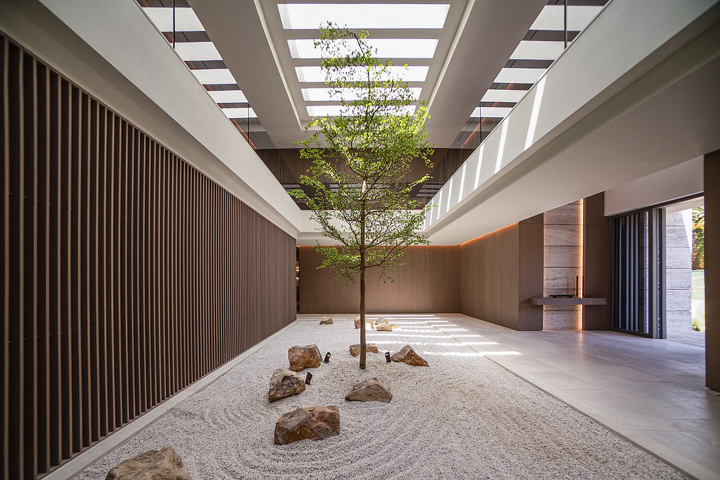 Sleek, minimalist hallway with a lone tree and gravel garden creating a serene indoor oasis.
