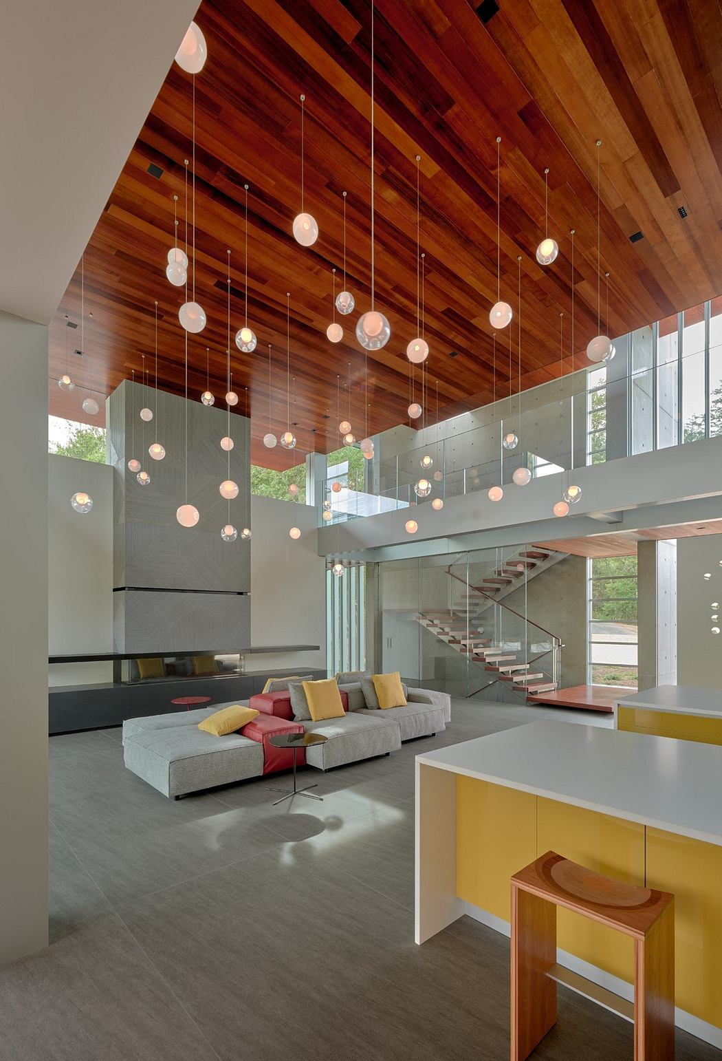 Sleek modern interior with wooden ceiling, pendant lights, and glass staircase.