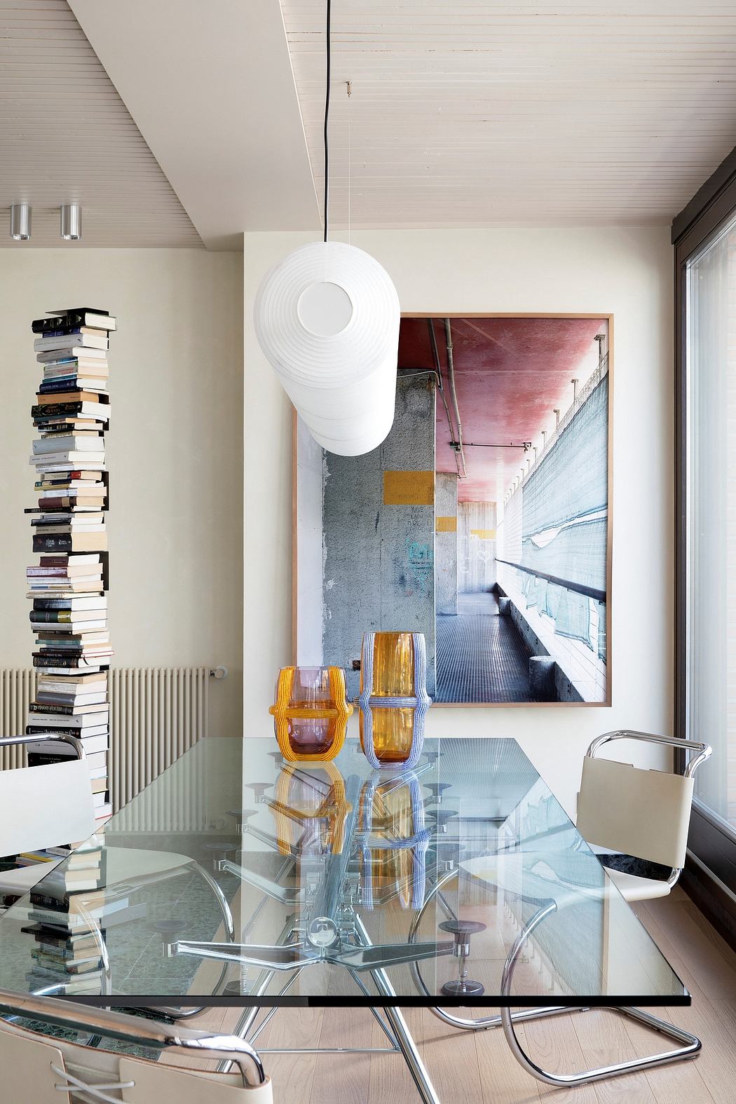 Minimalist living room with wooden ceiling, glass table, and colorful vases.