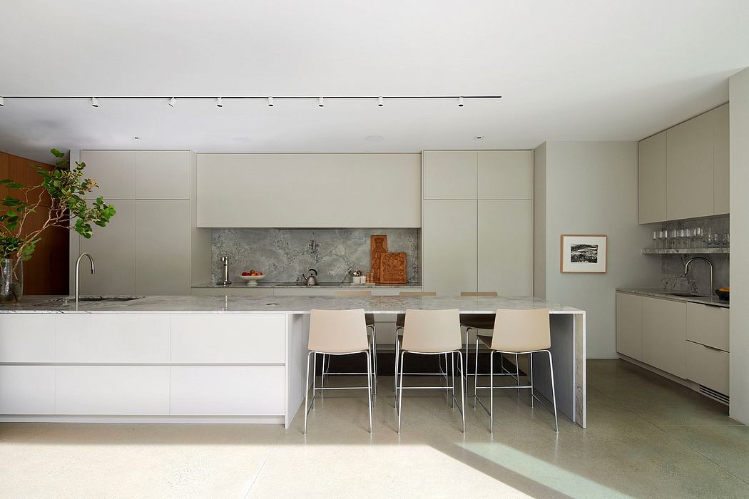 Minimalist kitchen with sleek white cabinets, marble backsplash, and modern bar stools.
