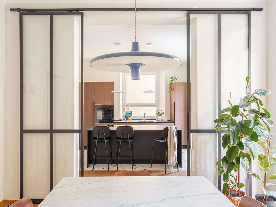 Modern kitchen with sleek black and white design, large pendant light, and sliding glass doors.