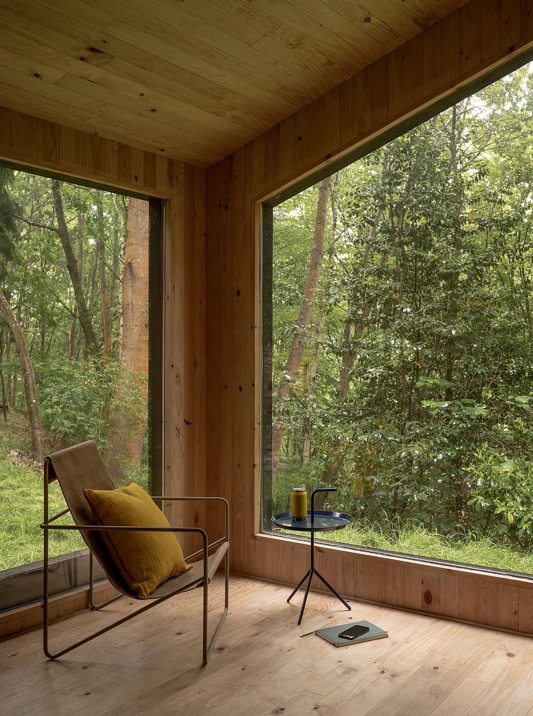 A cozy wooden cabin interior with expansive windows overlooking a lush forest.