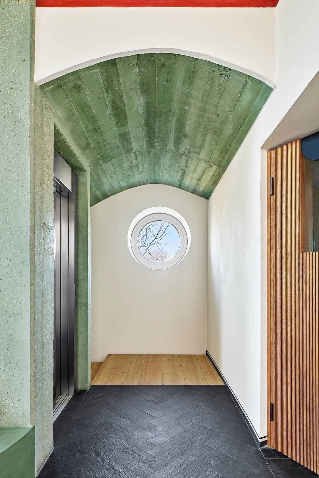A green tiled arched ceiling, round window, and slate floor create an architectural statement.