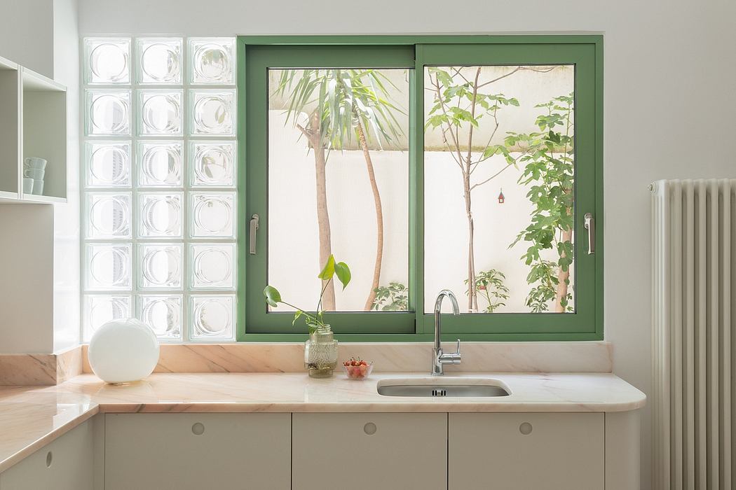 Bright, airy kitchen with green framed windows overlooking lush greenery.