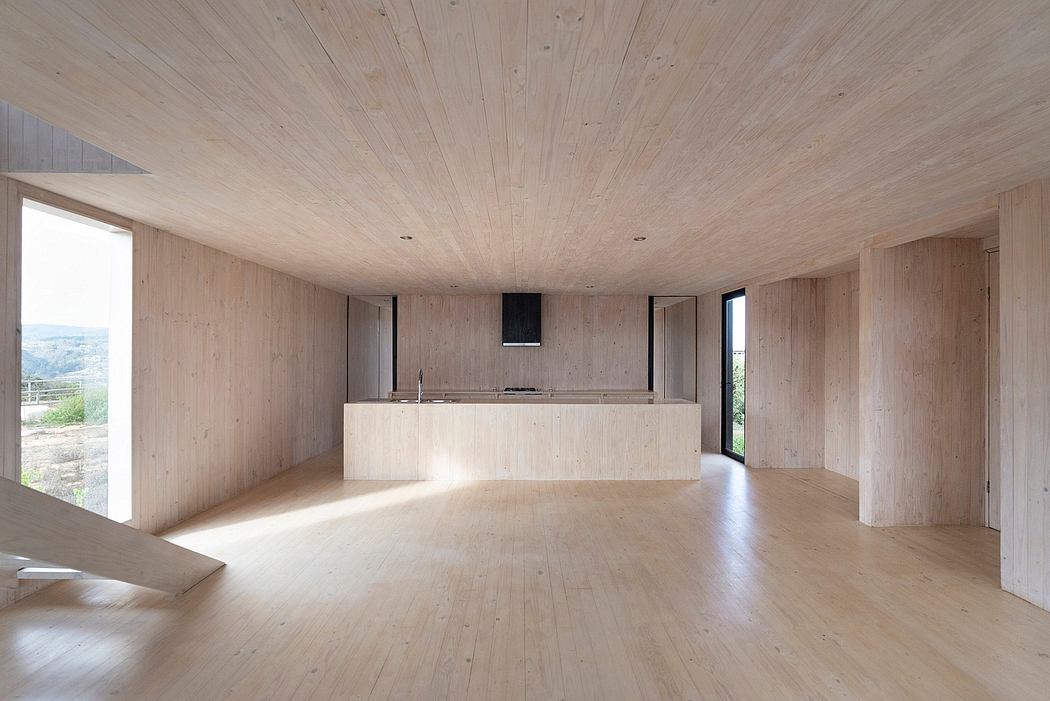 Expansive open-plan space with natural wood paneling and a minimal kitchen island.