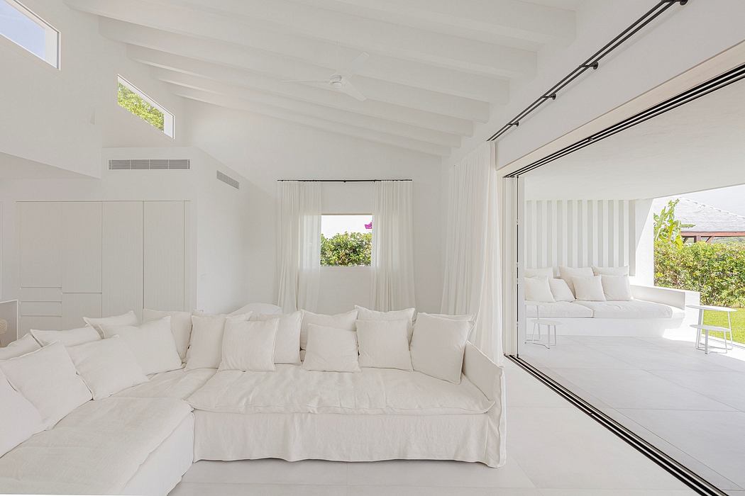 Bright, spacious living room with white furniture, large windows, and clean architectural lines.