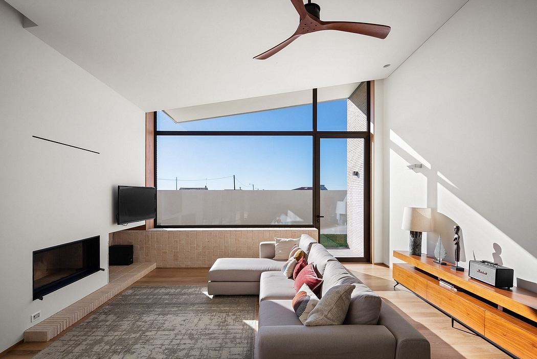 Spacious living room with large windows, modern ceiling fan, and sleek furniture.