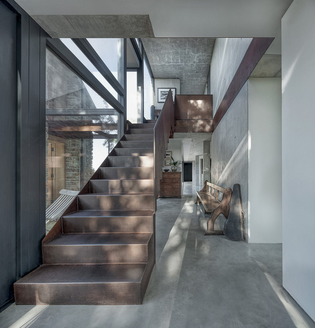 A modern, minimalist staircase with concrete steps and a bench in a spacious, industrial-style interior.