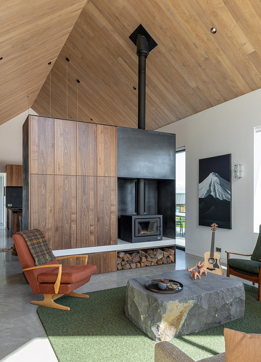A spacious, modern living room with a wood-paneled ceiling, a sleek fireplace, and an array of rustic and contemporary furnishings.