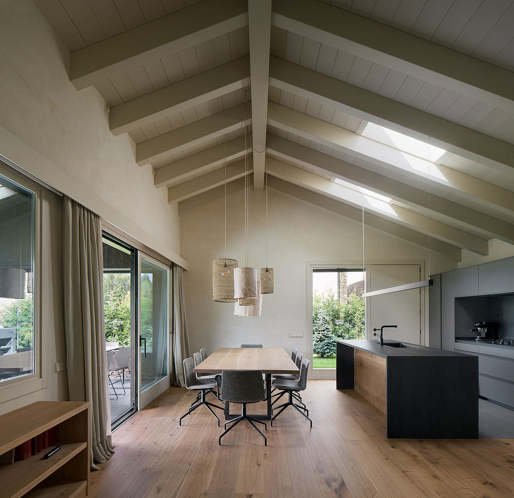 Vaulted beamed ceiling, wooden floors, modern furniture, and large windows overlooking lush garden.