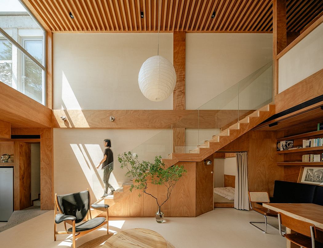 Spacious, modern interior with exposed wood beams, glass stairway, and natural lighting.
