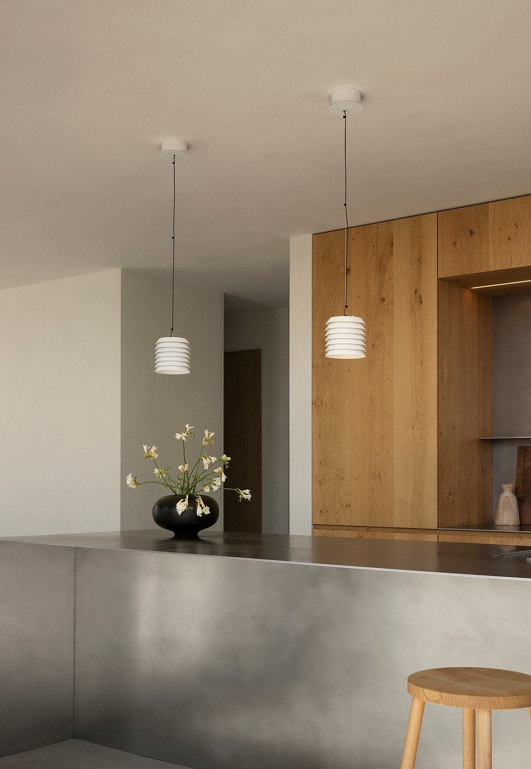 Minimalist kitchen with pendant lights, wood paneling, and a sleek stainless steel countertop.