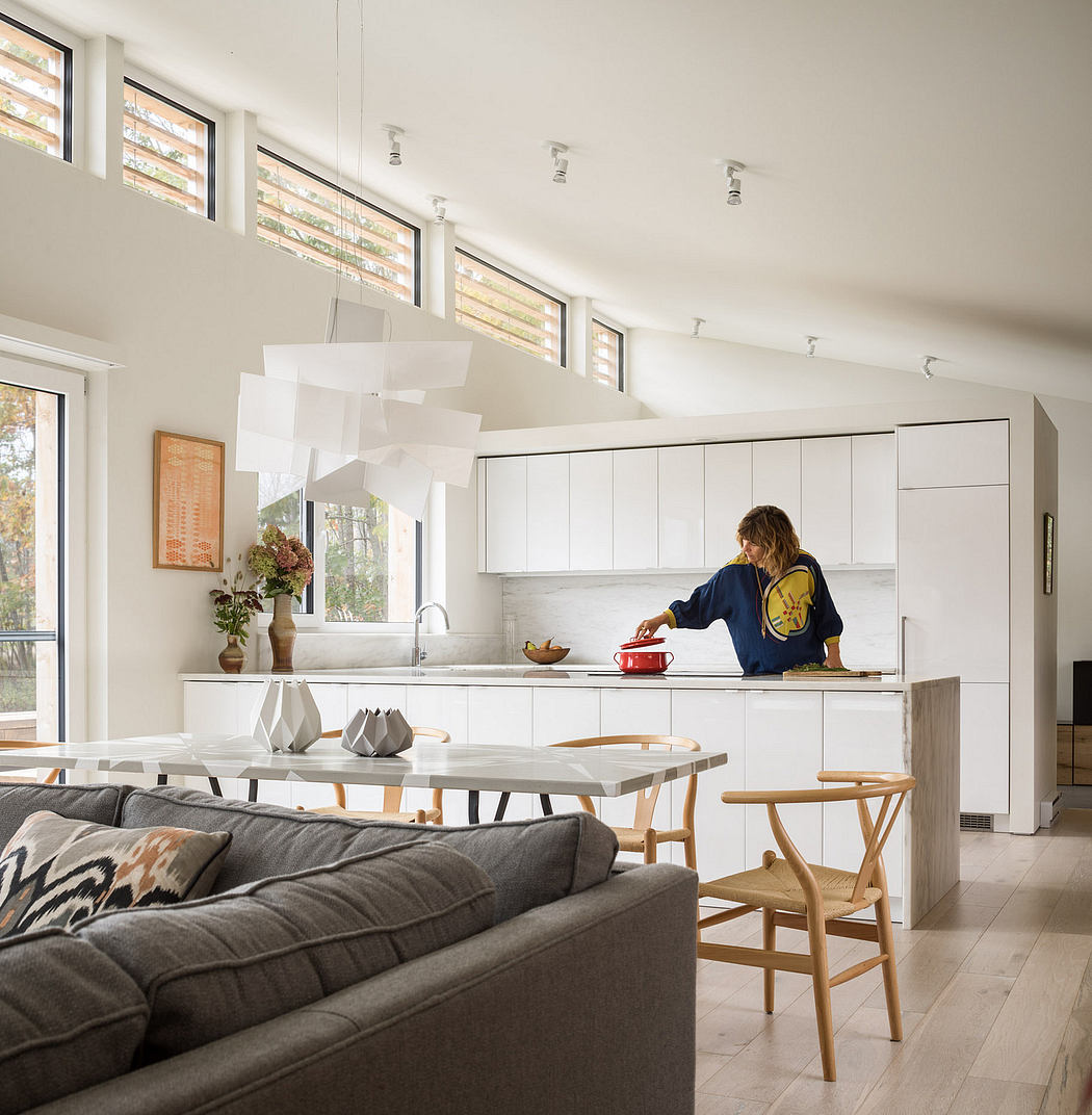 Bright, airy kitchen with modern cabinets and lighting; adjacent living area with couch.