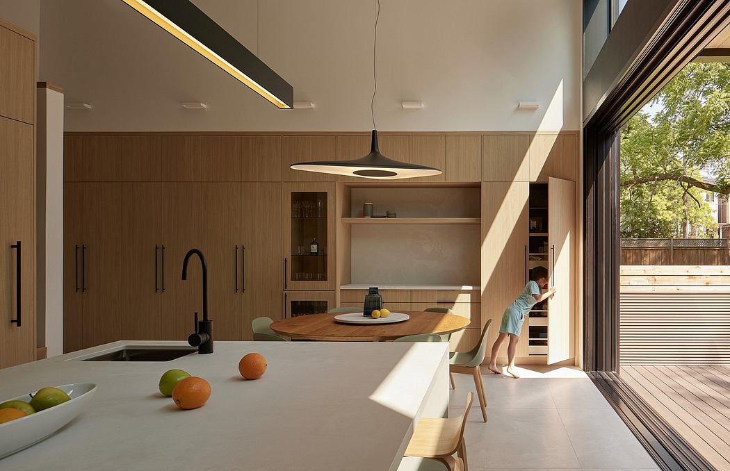 A modern kitchen with clean lines, wooden cabinetry, and a large window overlooking a patio.