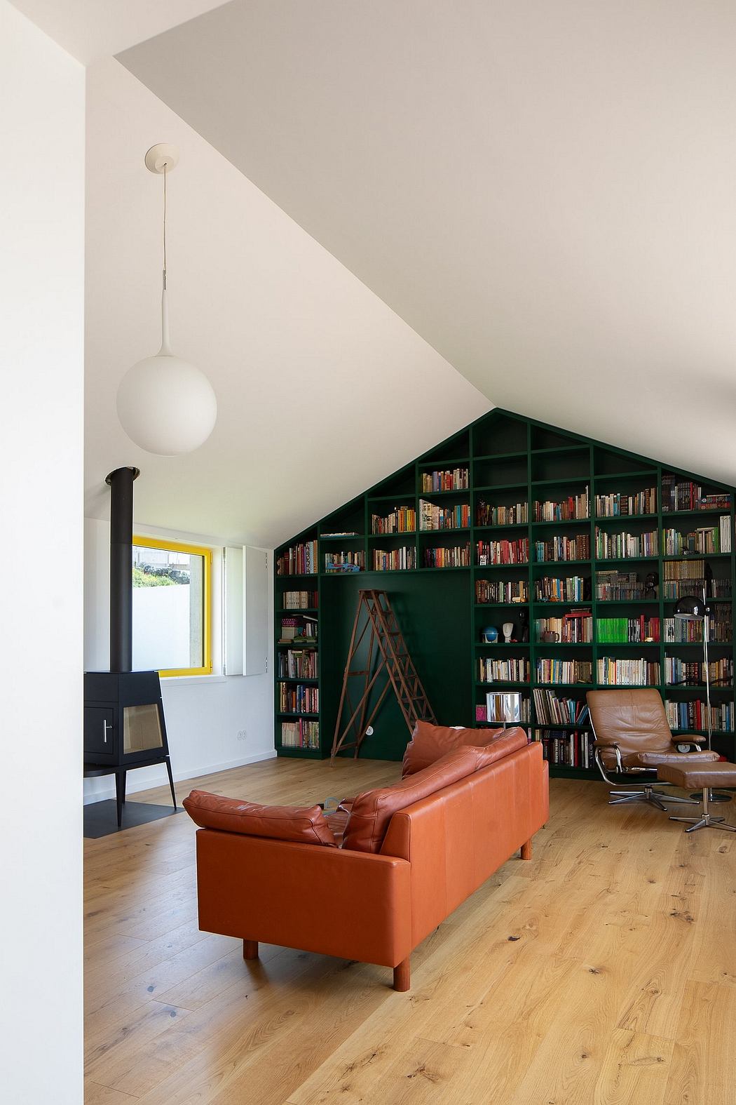 A cozy living space with an extensive built-in bookshelf, a leather sofa, and a wood-burning stove.