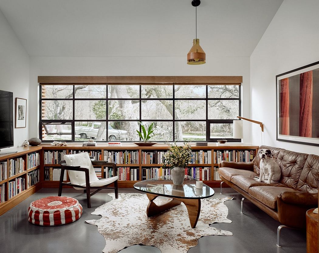 Spacious living room with wooden shelves, textured rug, and large windows showcasing outdoor greenery.