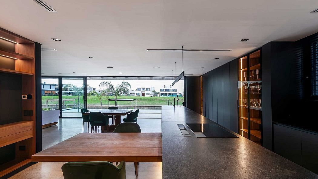 A modern, minimalist dining area with large windows overlooking a grassy landscape.