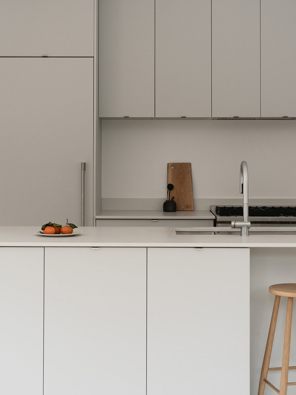 Minimalist kitchen design with white cabinetry, wooden accents, and a modern sink fixture.
