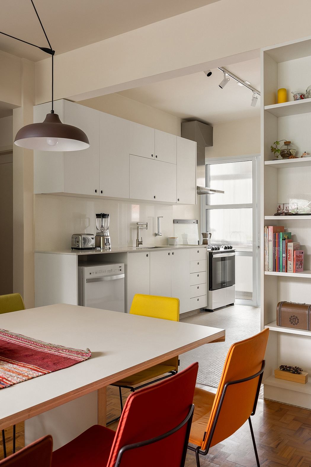 Minimalist kitchen design with sleek cabinetry, open shelving, and vibrant accent chairs.