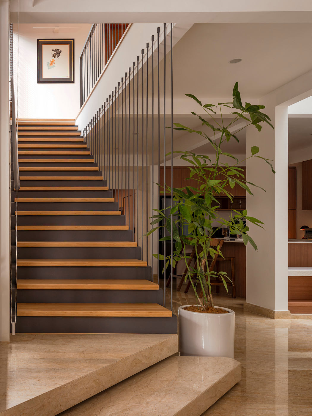 Elegant wooden staircase with sleek metal railings and a vibrant plant accent.