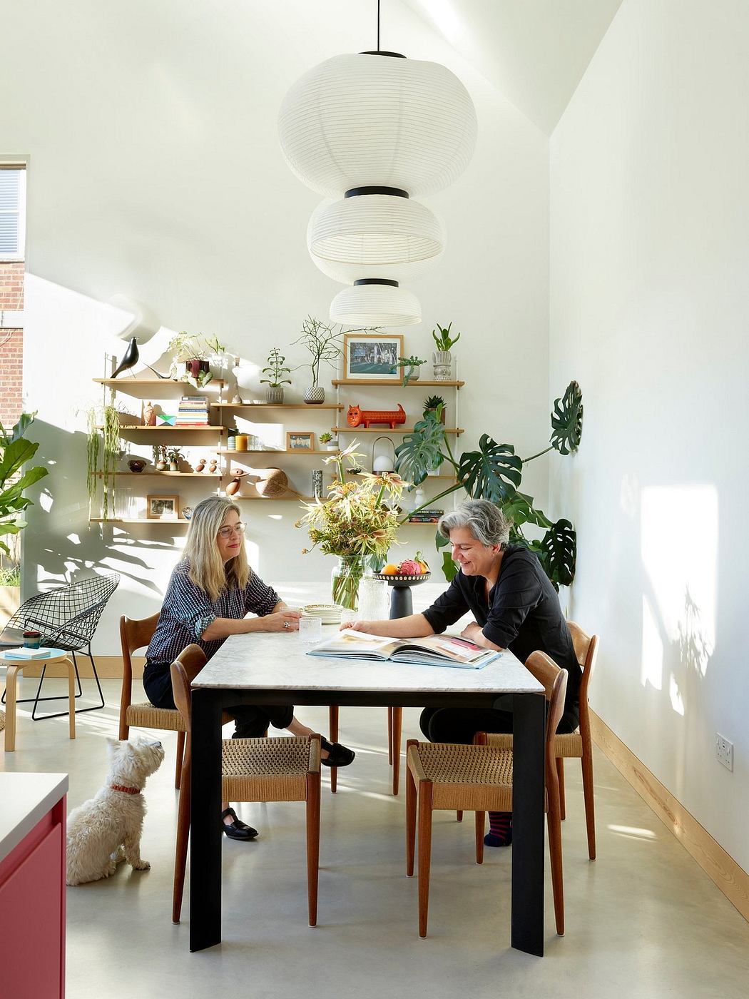 The image showcases a vibrant, modern interior with minimalist furniture, plants, and atmospheric lighting.