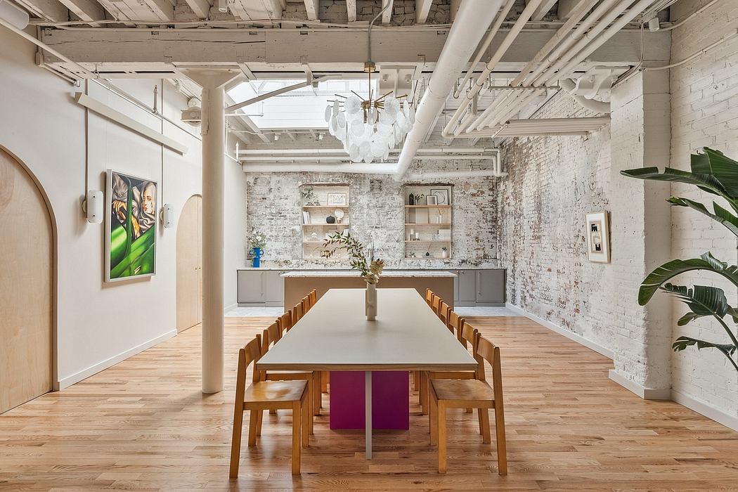 A spacious open-concept loft with exposed brick walls, wooden floors, and a large dining table.