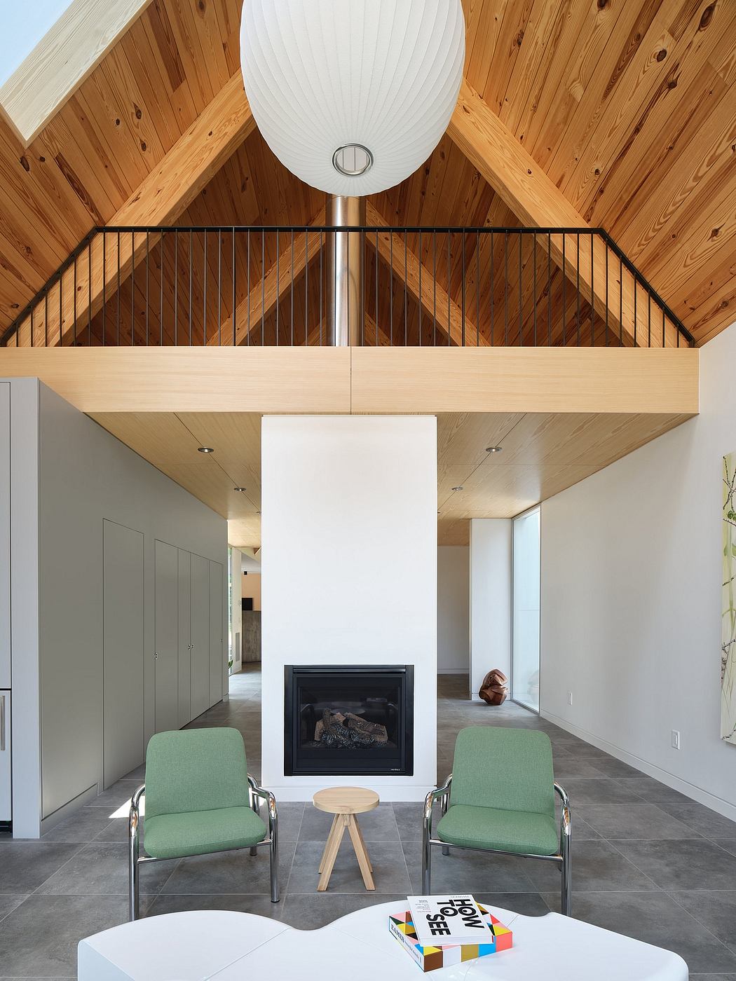 Expansive open-concept interior with wood-paneled ceilings, fireplace, and mid-century style furniture.