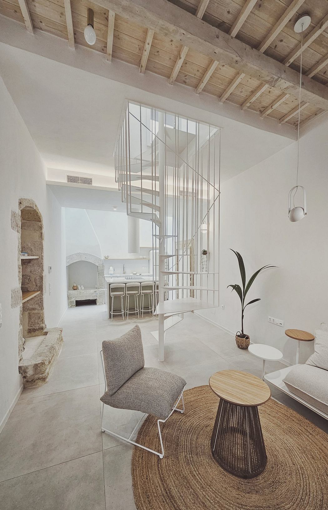 Modern open-concept living space with exposed wooden beams, spiral staircase, and neutral decor.