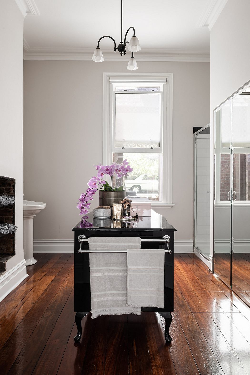 Elegant bathroom interior with ornate black vanity, plush towels, and vibrant orchid display.
