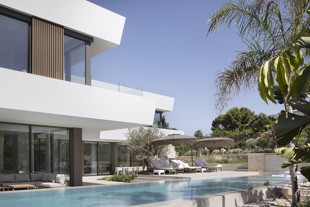 Modern, minimalist villa with glass walls, pool, and lush tropical landscaping.