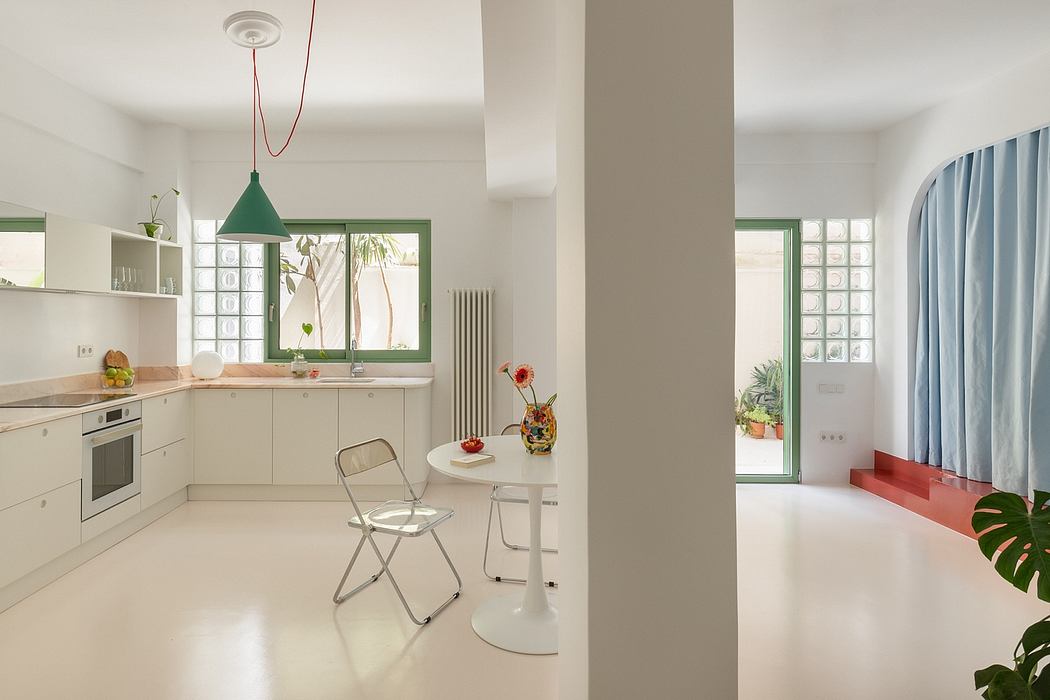 A minimalist kitchen with a green pendant light, white cabinets, and glass block windows.