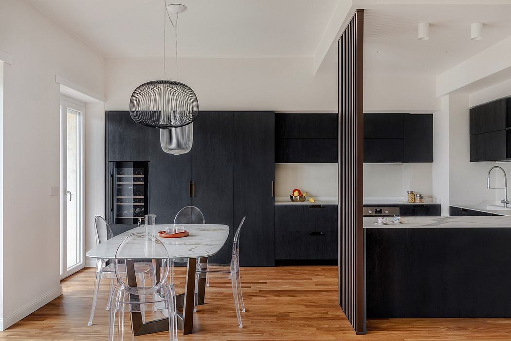Modern kitchen with sleek black cabinetry, marble countertops, and a striking pendant light.