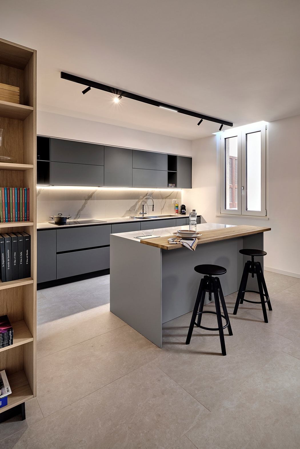 Sleek modern kitchen with matte black cabinets, wood countertop, and track lighting.
